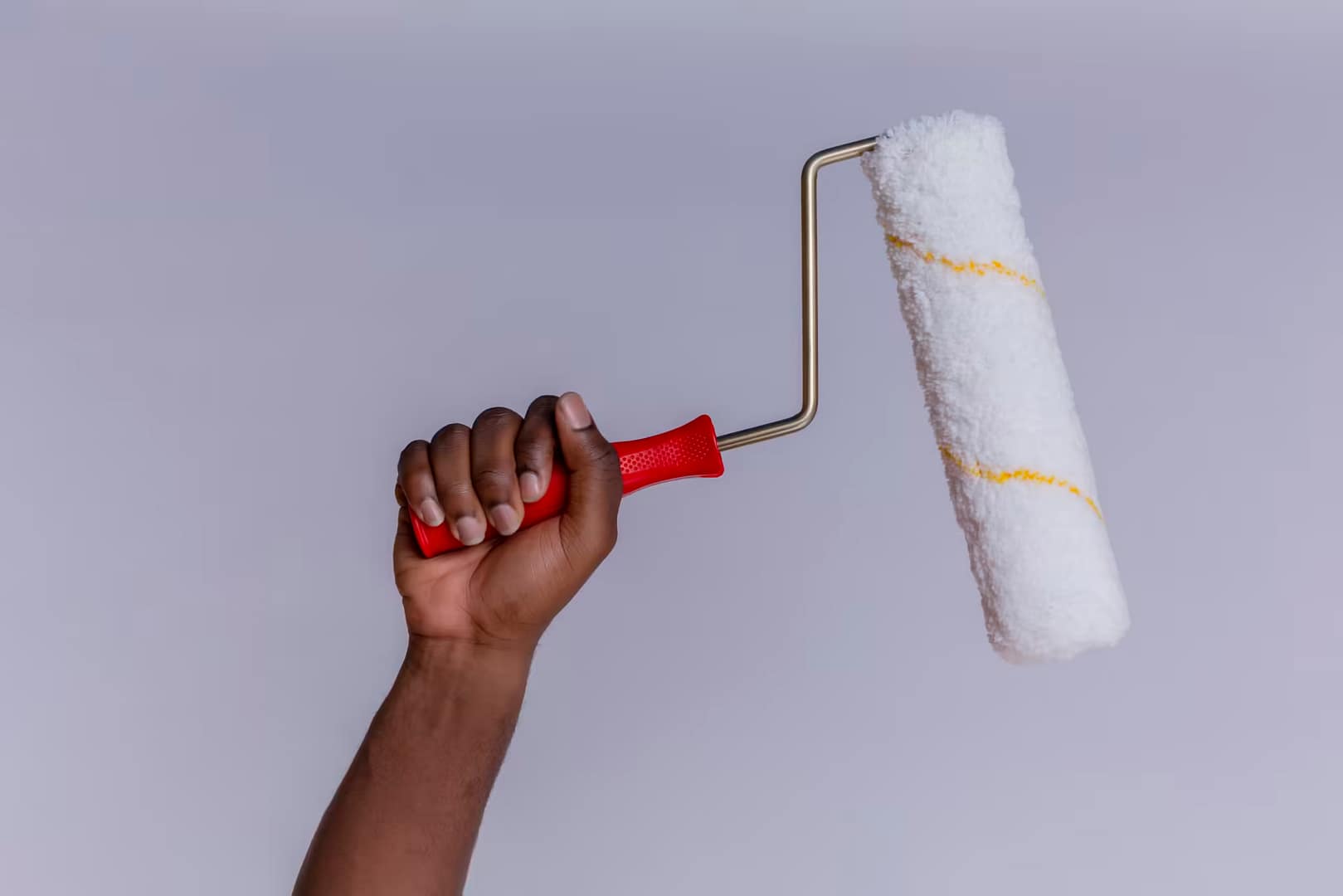 side view of hand with paint roller over isolated white background